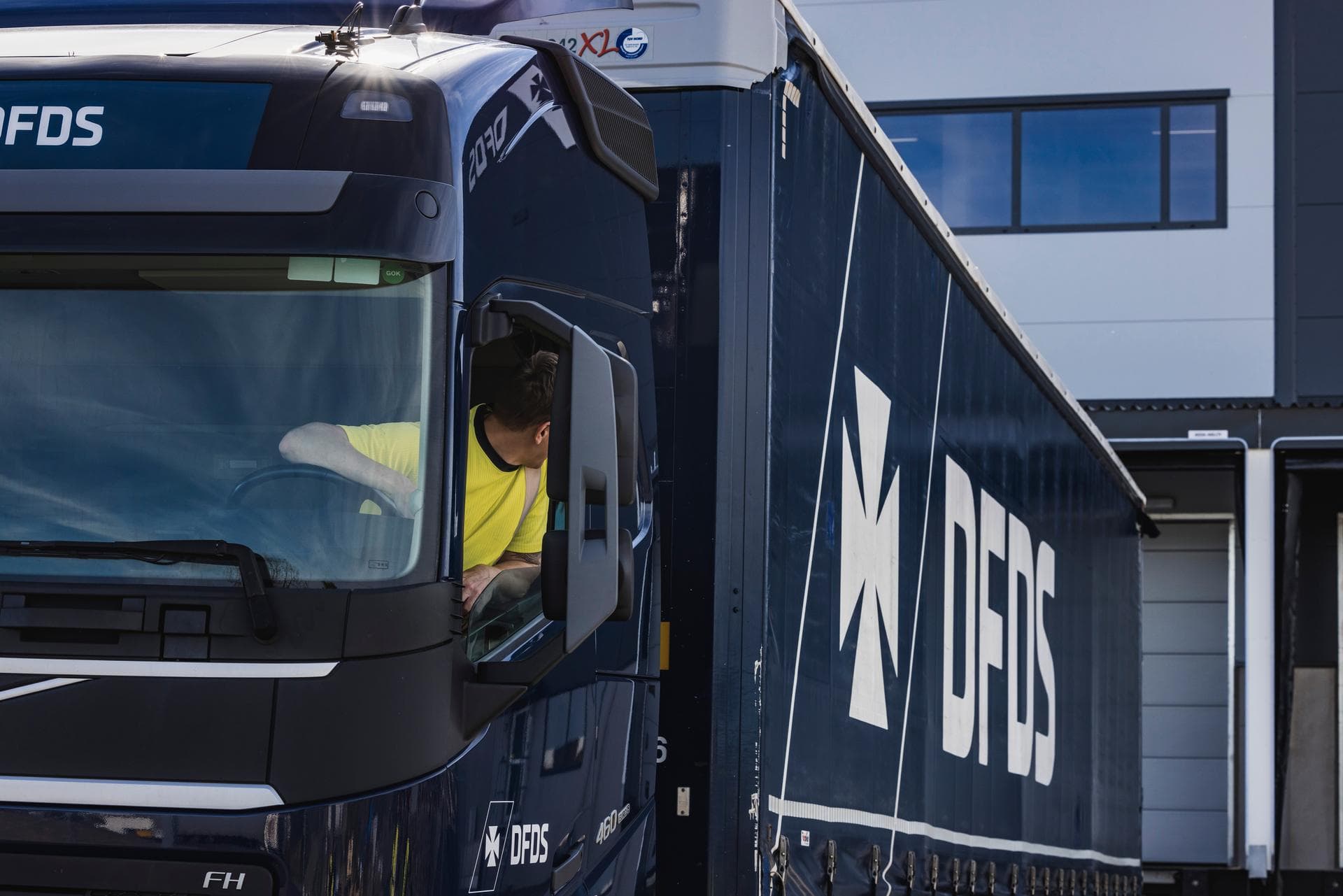 Blue DFDS truck being backed up by truck driver.