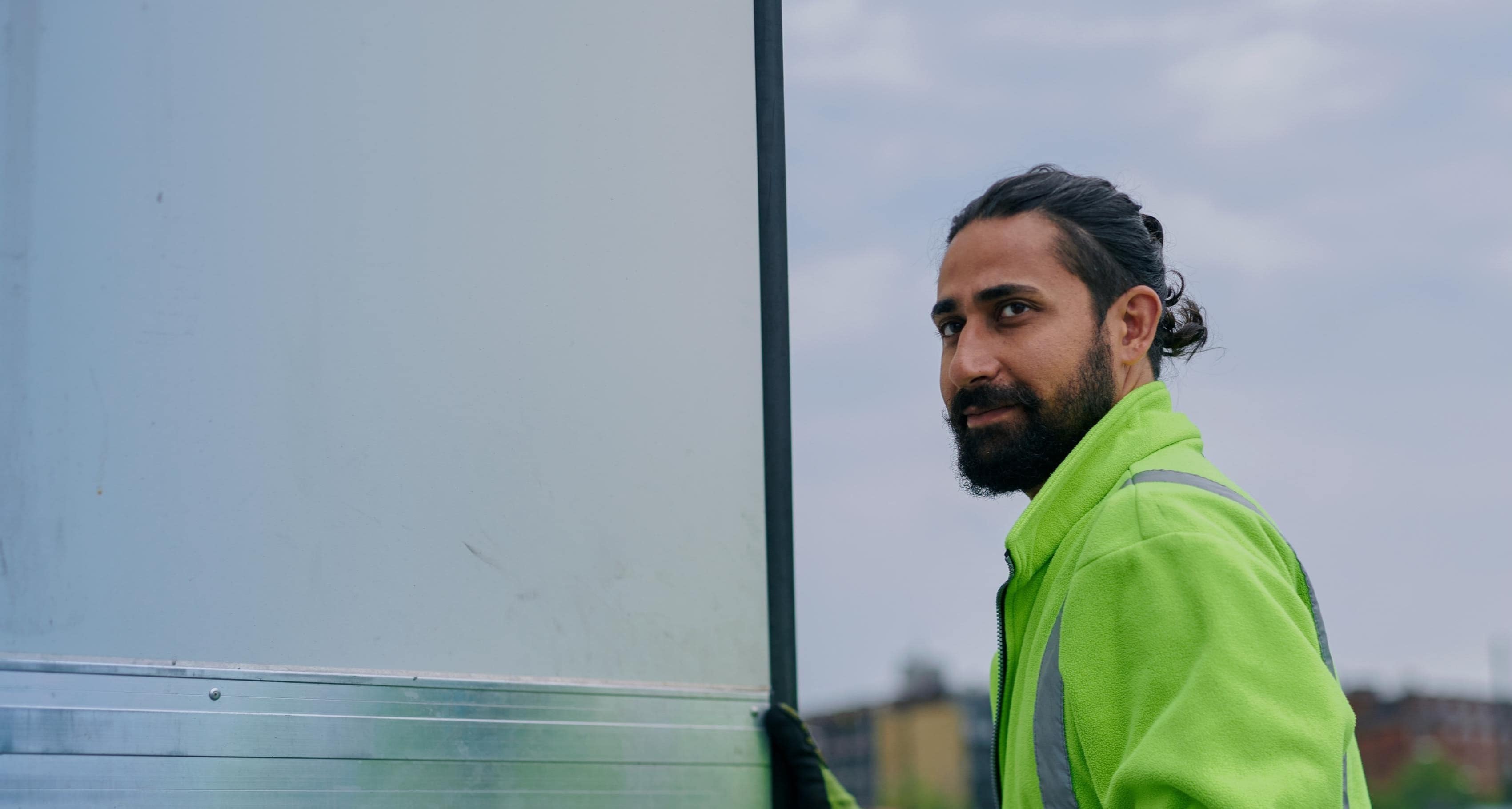 A DFDS employee wearing a high visibility jacket stands next to a trailer and looks towards his left-hand side