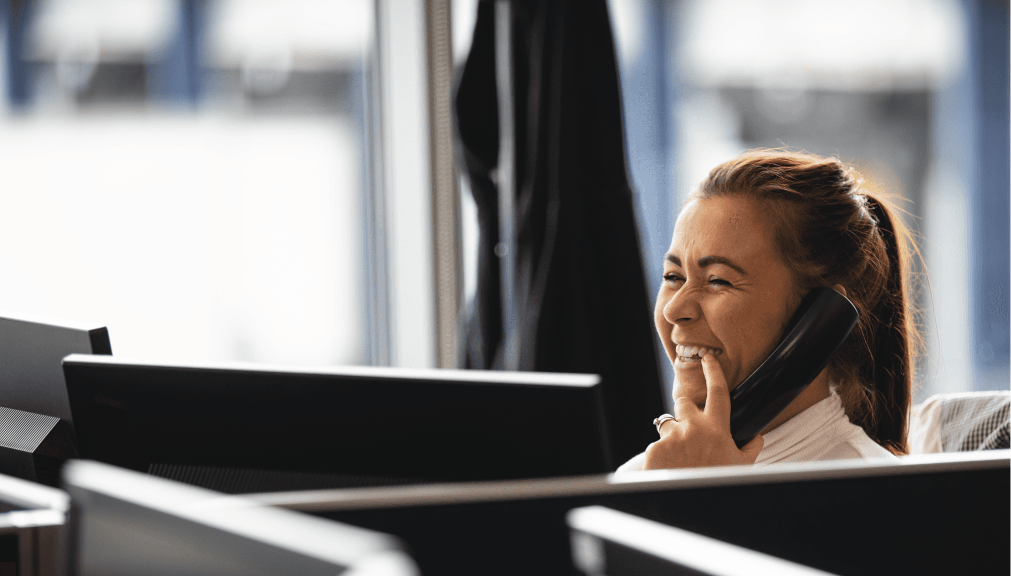 Photo of a DFDS Customer Service employee smiling while on the phone in the office
