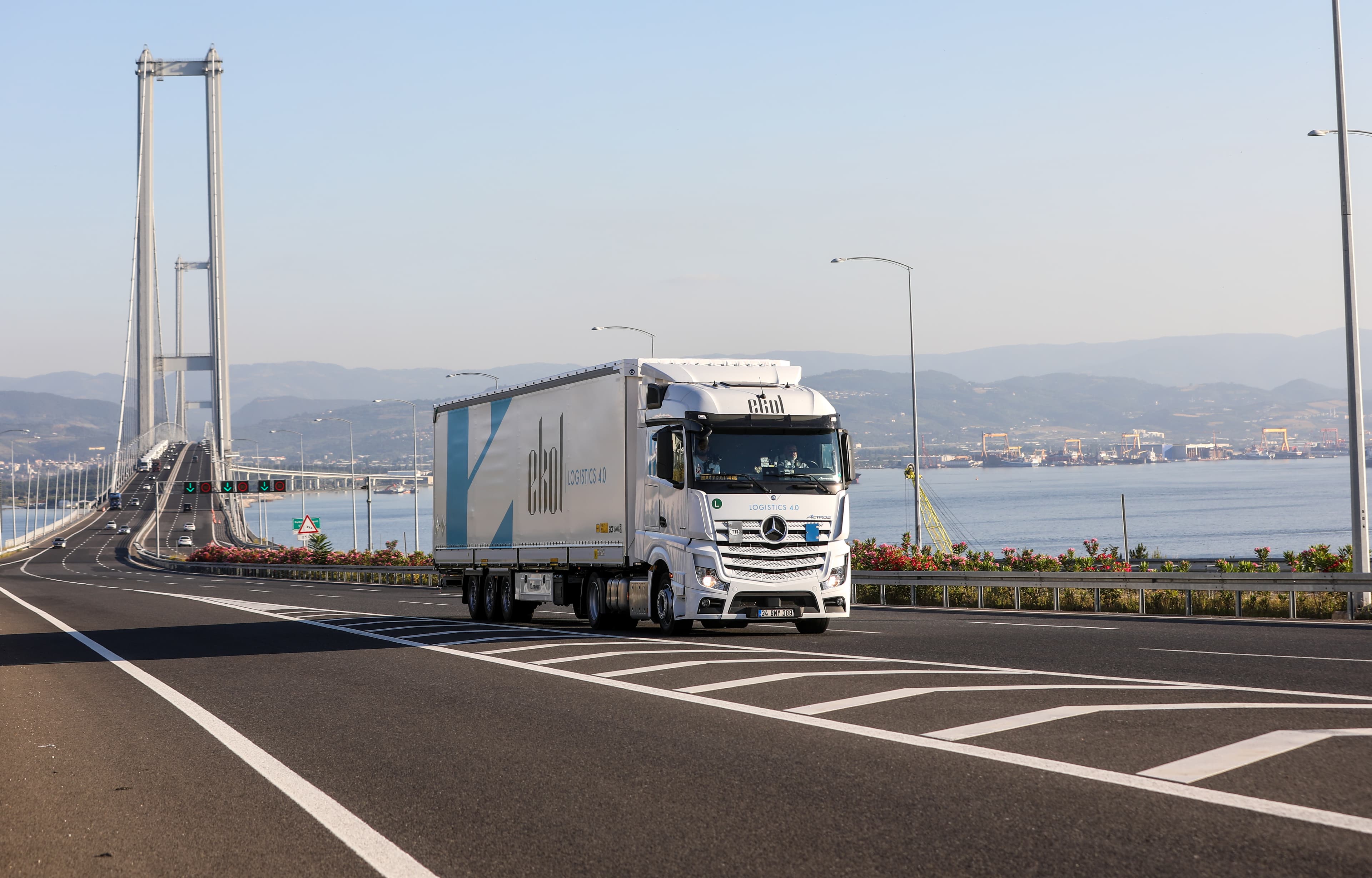 An EKOL truck, in that specific livery, driving on a highway in Türkiye, within the background the bridge over the Bosporus