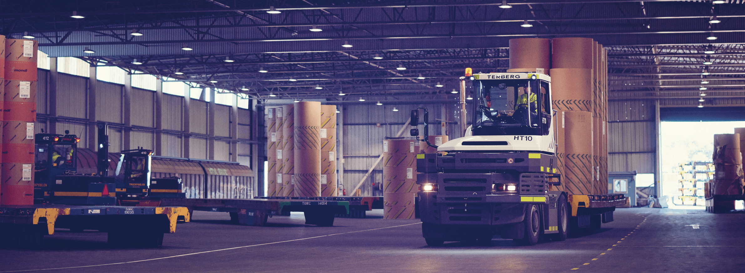 A terminal tractor loading paper rolls onto a DFDS Logistics warehouse