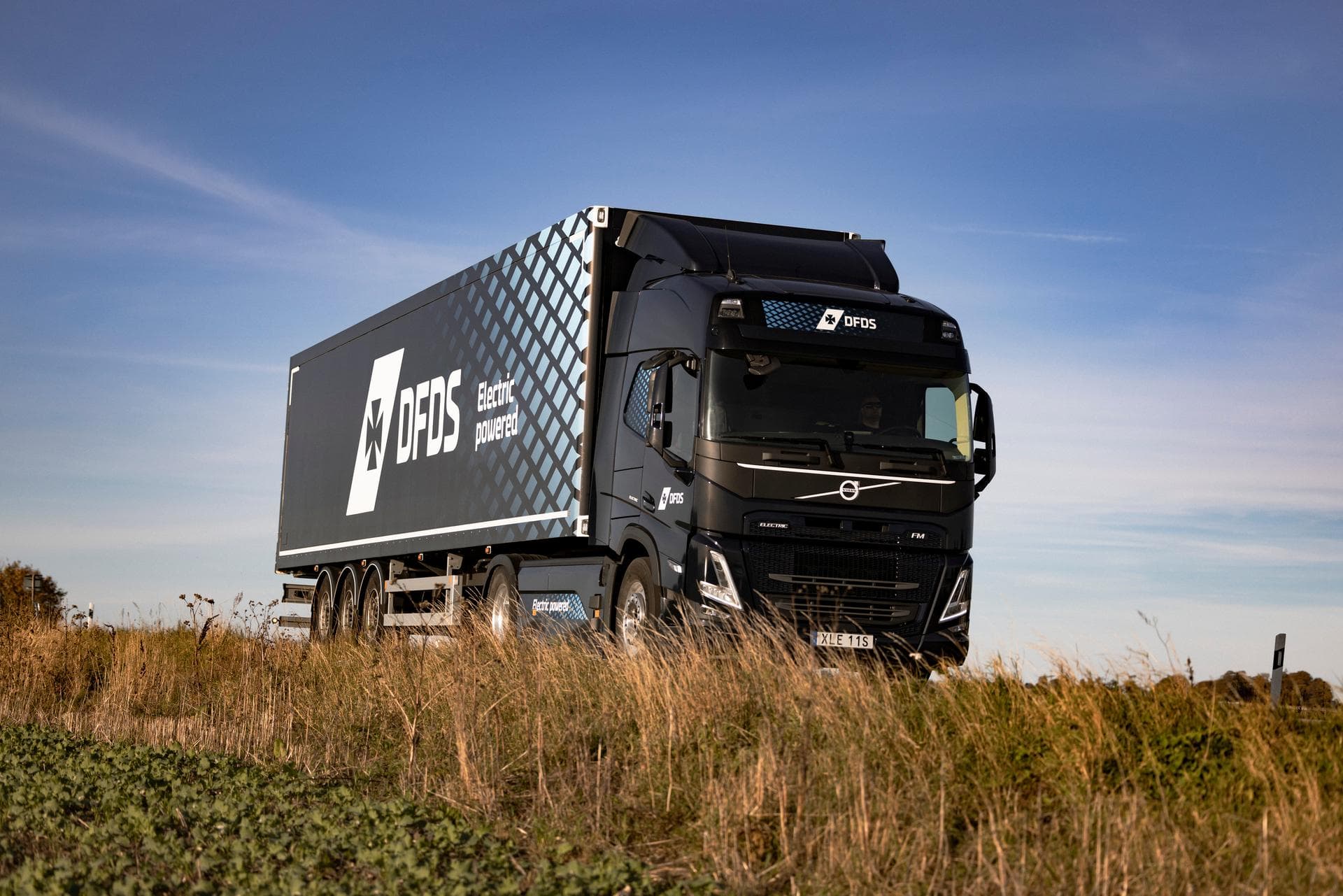 Volvo electric truck, with dark blue trailer, with DFDS logo on the side