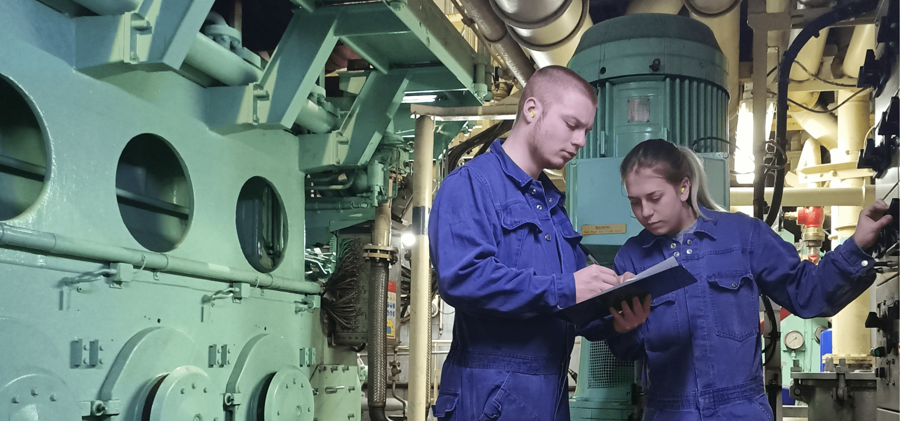 Two DFDS employees look over a sheet inside a vessel's engine room