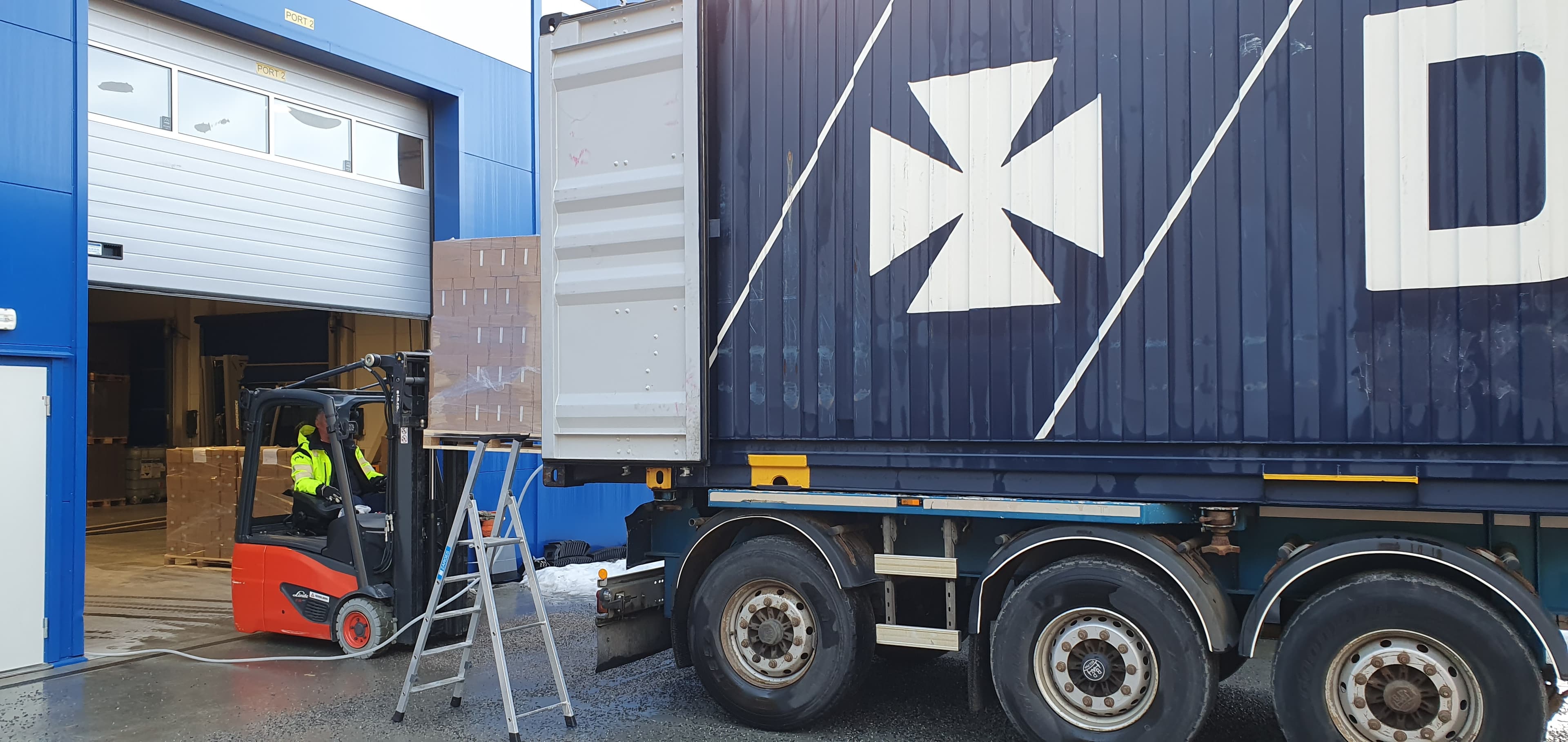 A DFDS 45ft container, getting loaded with a forklift truck, with pallets stacked with bottles of drinking water