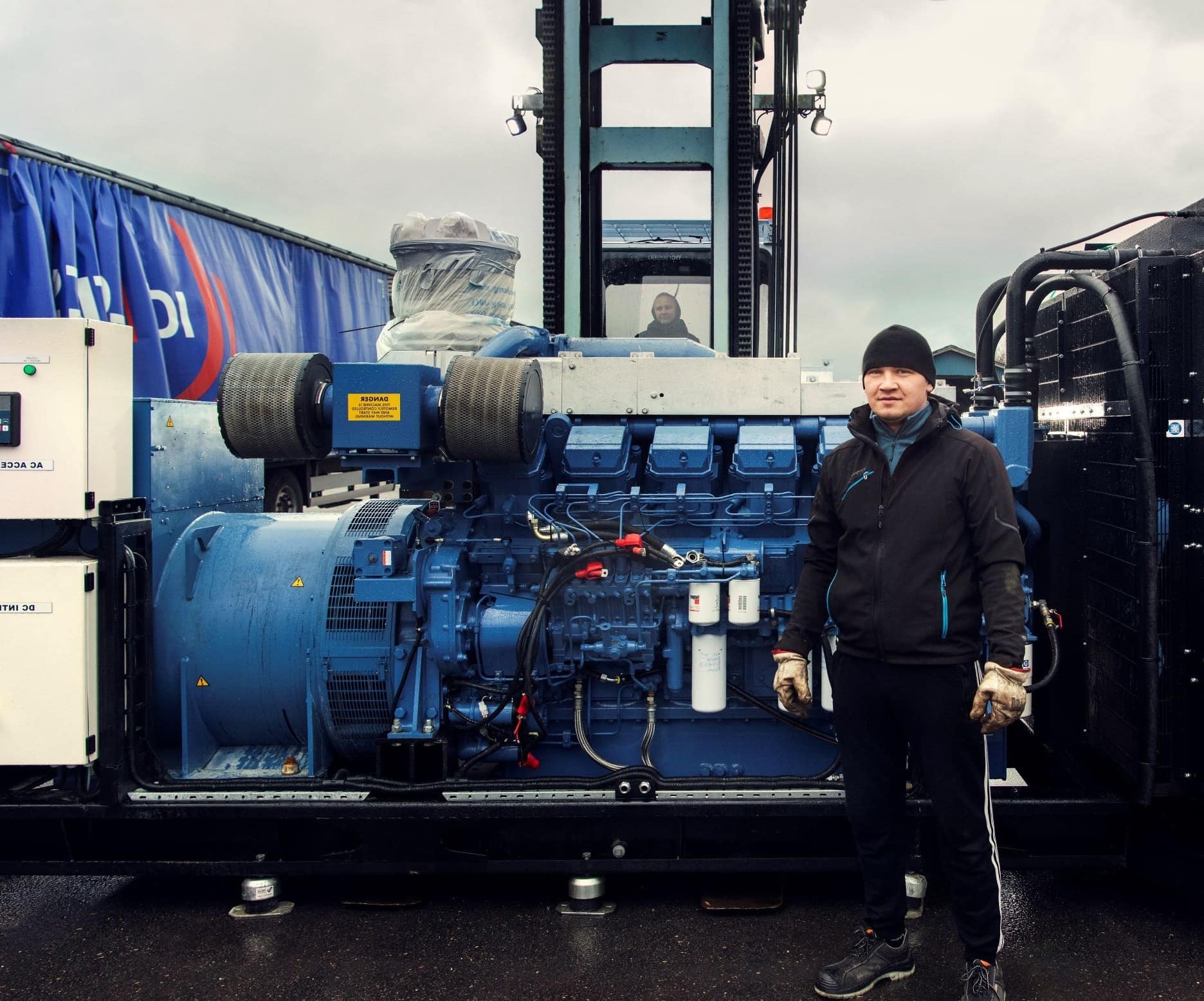 DFDS' truck driver Yurii Rozhkov stands in front of a blue engine being transported on a forklift