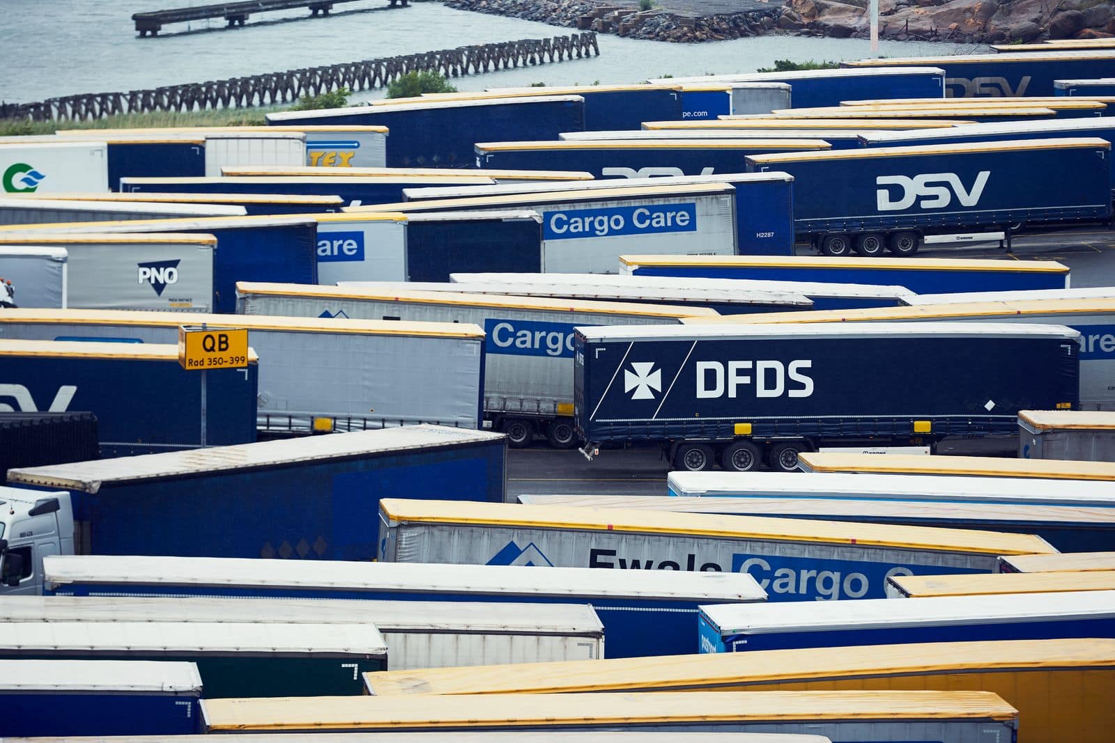 A dark blue DFDS freight and logistics trailer sits at a terminal surrounded by other trailers