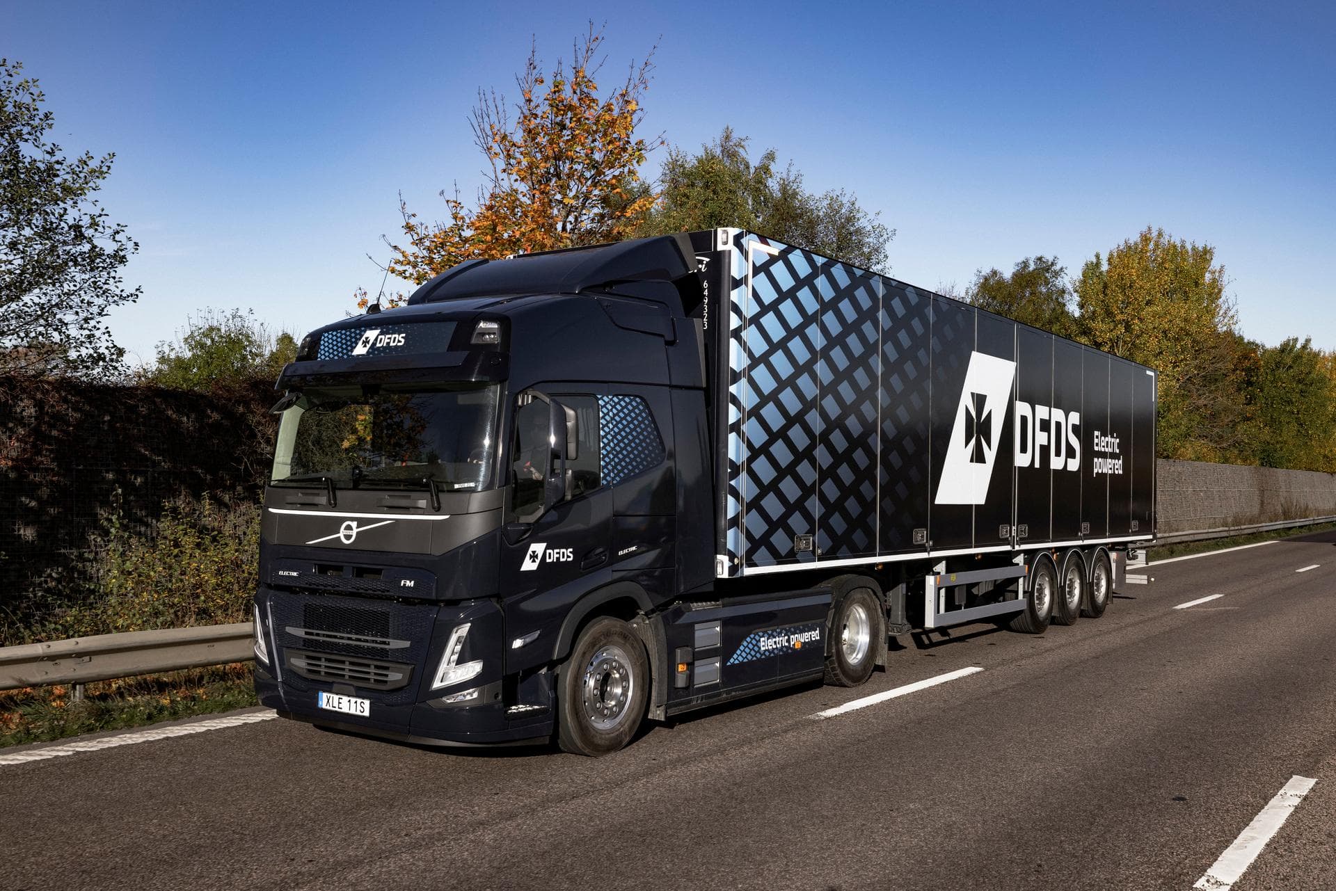 Electric truck in dark blue DFDS livery, driving on the road