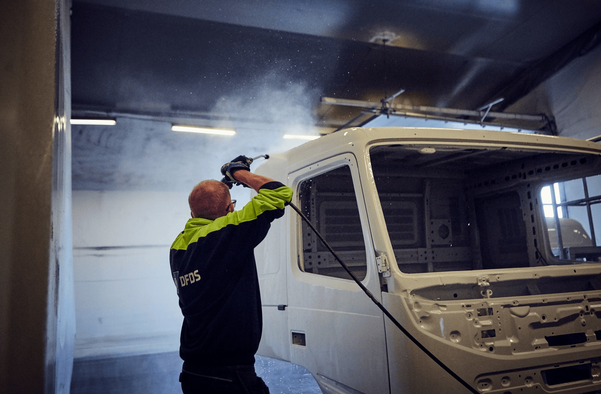 A man spraying the front of the truck with water