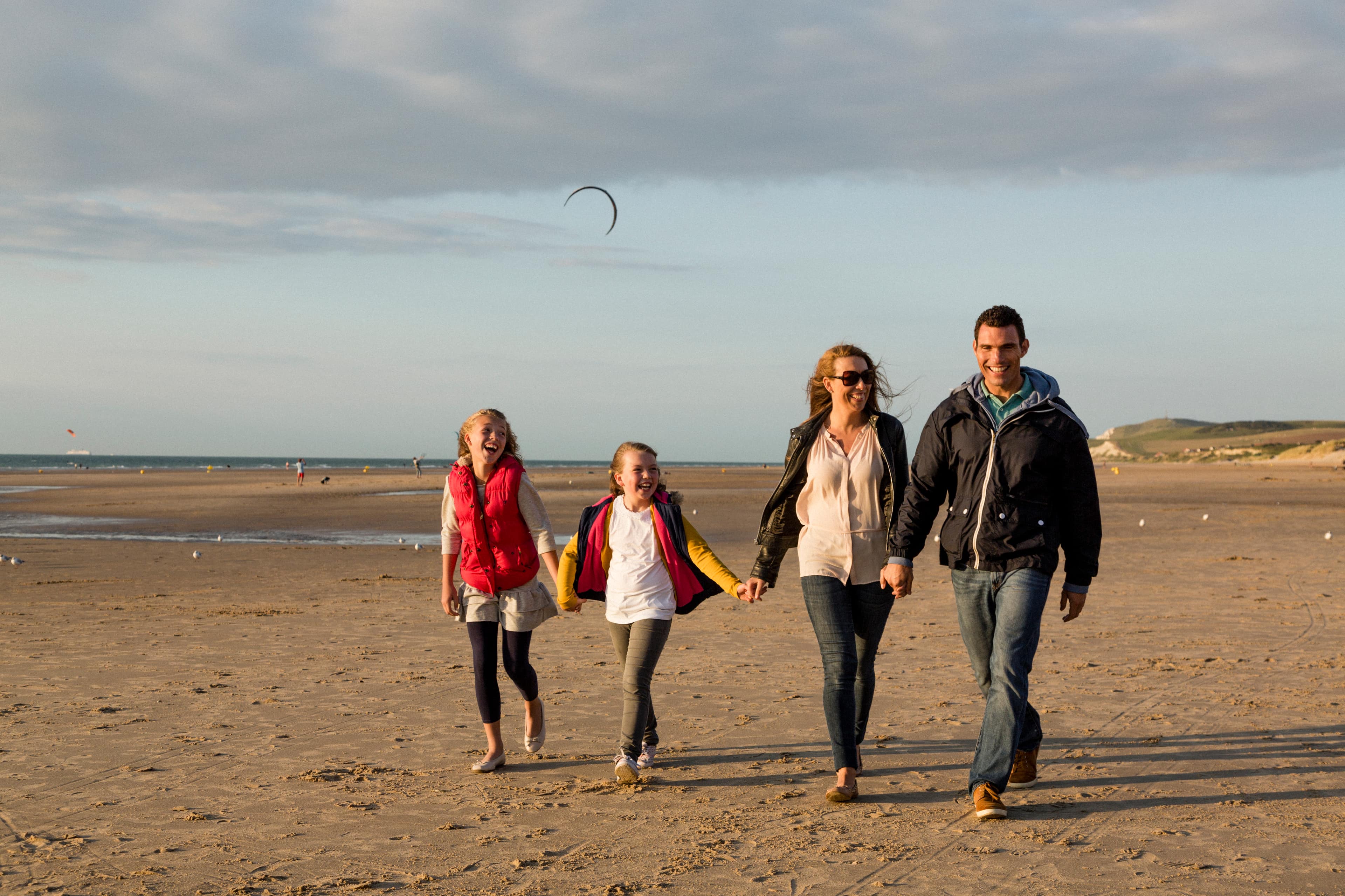 Familie geht am Strand entlang und hält sich an den Händen